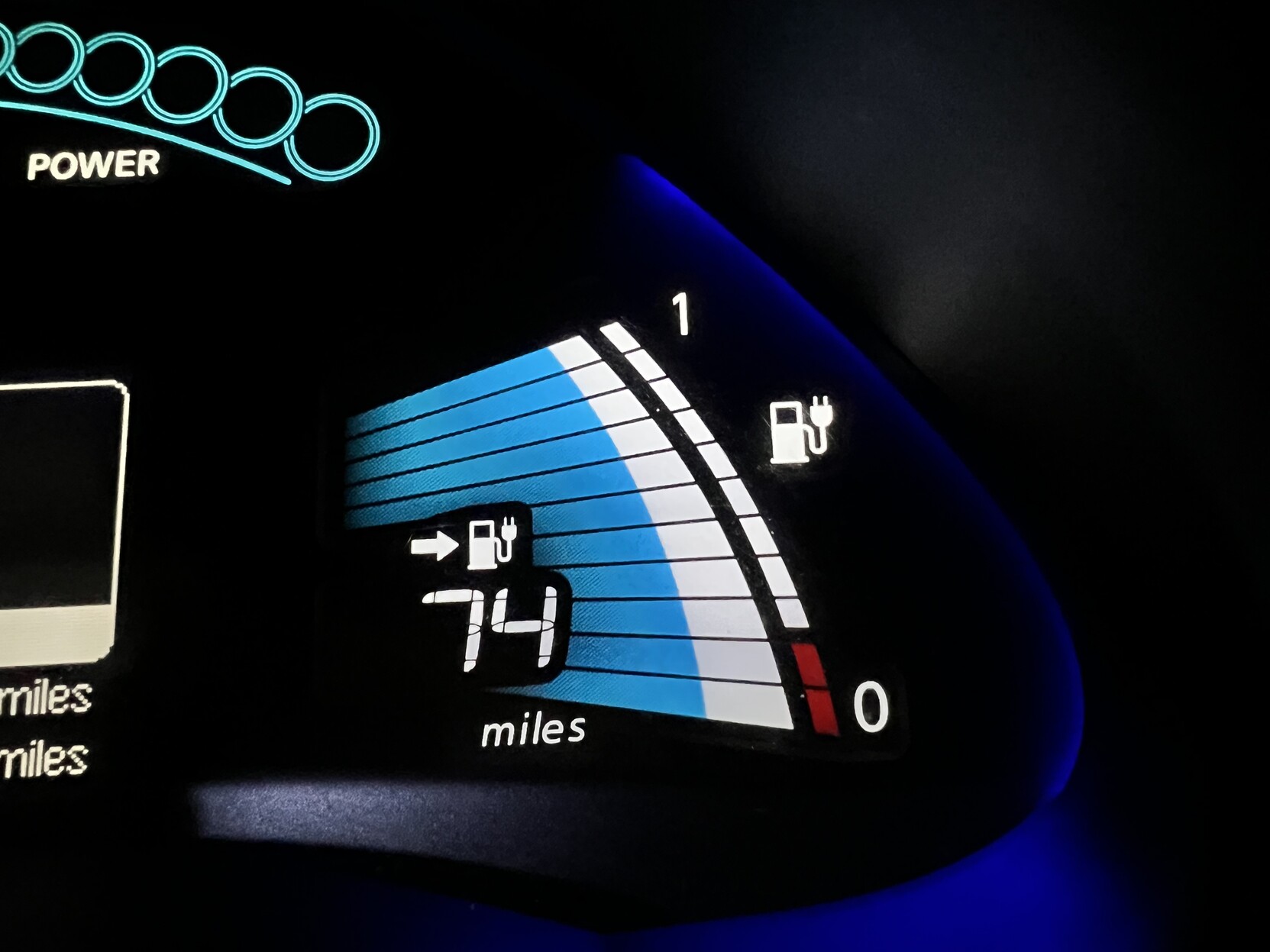 Car dashboard showing battery bars and 74 miles range.